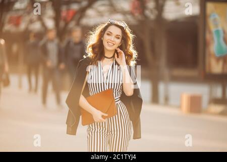 Bella ragazza sorridente in elegante primavera guardare a piedi per strada. Foto Stock