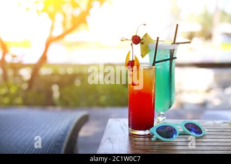 Vetro con una laguna blu luminosa e cocktail all'alba in tequila presso la piscina Foto Stock