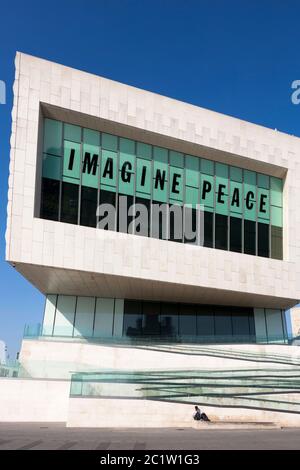 Lone Man si trova fuori dal Museum of Liverpool, che mostra il tag John Lennon, 'Imagine Peace', Pier Head, Liverpool, Inghilterra, Regno Unito Foto Stock