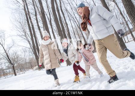 La famiglia felice in esecuzione nella neve Foto Stock