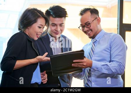 Gruppo di tre brand manager che lavorano insieme per il piano aziendale guardando lo schermo del tablet digitale Foto Stock