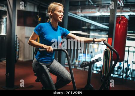 Montare la donna che lavora fuori sulla cyclette in palestra Foto Stock