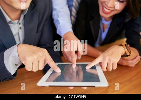 Gruppo di tre persone che lavorano insieme utilizzando un tablet, toccando lo schermo con le dita Foto Stock