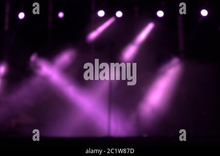 Luci viola sfocate su un palco che creano un'atmosfera per un concerto di musica moderna, pop o rock Foto Stock