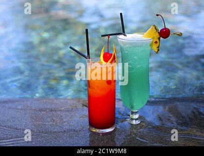 Vetro con una laguna blu luminosa e cocktail all'alba in tequila presso la piscina Foto Stock