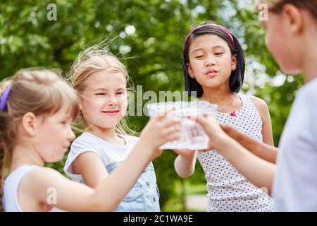 Gruppo di bambini con tazze di plastica mentre beve acqua in estate Foto Stock