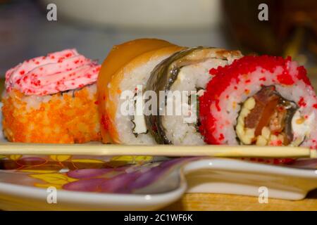 Rotoli di Sushi con salmone, anguilla, crema di formaggio Philadelphia, caviale tobica e bastoni di cibo sulla piastra Foto Stock
