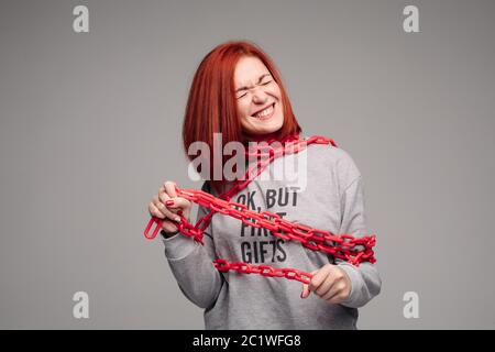 Ragazza impigliate in una catena,un i capelli rossi donna con capelli castani cerca di sbarazzarsi della catena Foto Stock