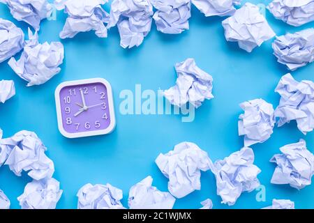 Orologio quadrato con palline di carta bianca su sfondo blu. Vista dall'alto Foto Stock