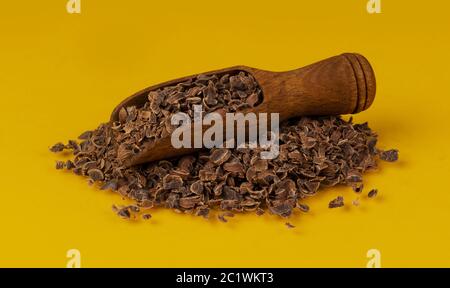 Cioccolato grattugiato. Pila di cioccolato macinato in paletta di legno isolata su sfondo giallo, primo piano Foto Stock