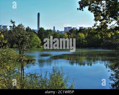 Lago tranquillo nella Riserva Naturale comune di Barlow vicino a Selby, North Yorkshire, Inghilterra, con le torri della centrale elettrica di Drax sullo sfondo Foto Stock