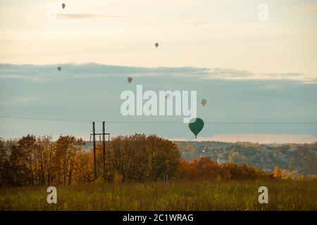 In una serata autunnale, i colorati mongolfiere volano contro il cielo nuvoloso della campagna Foto Stock