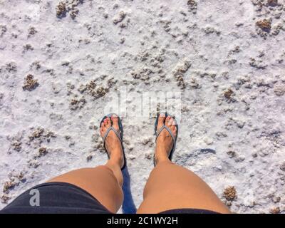 Donna in piedi sulla spiaggia nella zona marea con il sale residuo Foto Stock