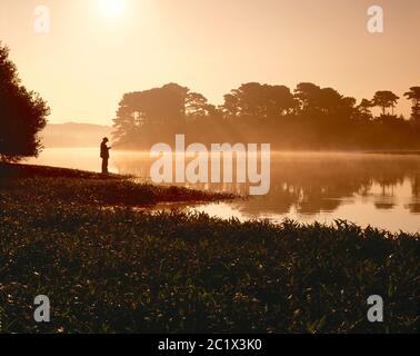 Guernsey. Uomo pesca al serbatoio in prima mattina. Foto Stock