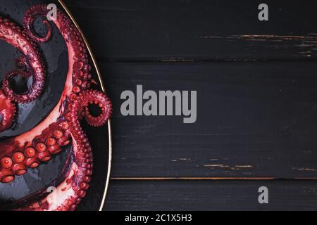 Tentacoli di polpo appena cucinato sulla vista dall'alto della piastra nera Foto Stock