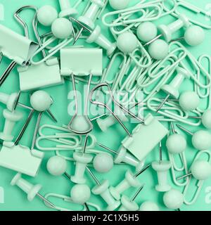 Trama composta da graffette e spille su sfondo mint. Concetto monocromatico. Foto Stock