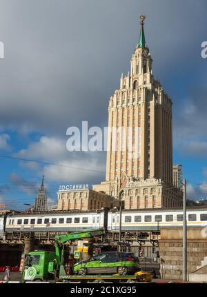 1 aprile 2019 Mosca, Russia. Un camion porta un'auto a un parcheggio sullo sfondo dell'edificio dell'hotel Leningradskaya sulla piazza di Foto Stock