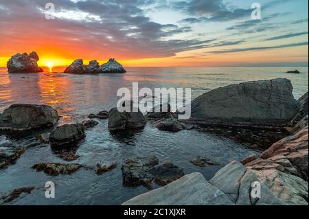 Tramonto sul mare e sulla riva in pietra Foto Stock