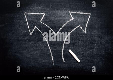 Due frecce di direzione come concetto di scelta e di decisione, gesso che attingendo su lavagna sporca Foto Stock