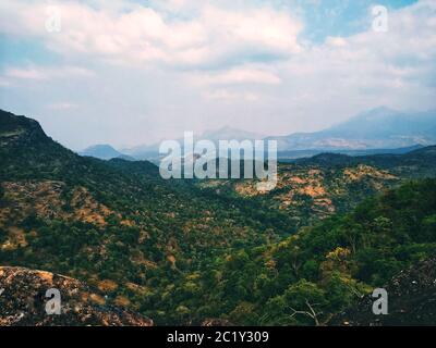 Una bella vista delle colline da una collina. Verde ovunque con nuvole che nascondono la bellezza di altre colline Foto Stock