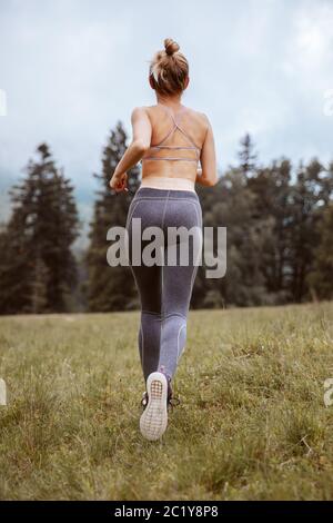 Irriconoscibile giovane ragazza sportiva che corre nella foresta nebbiosa. Concetto di stile di vita putdoor. Foto Stock