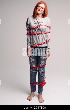 Ragazza impigliate in una catena,un i capelli rossi donna con capelli castani cerca di sbarazzarsi della catena Foto Stock