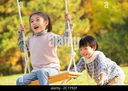 Felici i bambini sulle altalene nel parco Foto Stock
