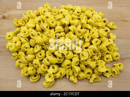 Tortellini non cotti su tavola di legno, pasta italiana Foto Stock
