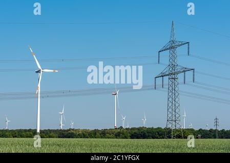 Linea elettrica aerea e delle turbine a vento visto in Germania rurale Foto Stock