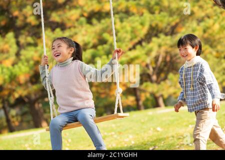 Felici i bambini sulle altalene nel parco Foto Stock
