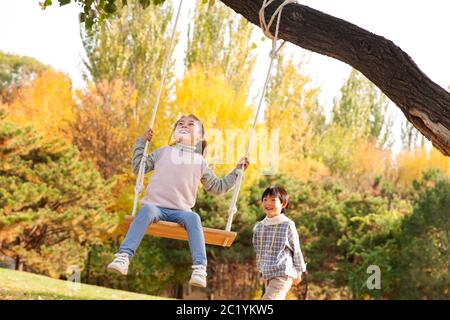 Felici i bambini sulle altalene nel parco Foto Stock