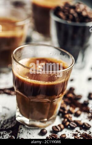 Caffè in tazze di vetro mescolate con crema e chicchi di caffè spruzzati Foto Stock