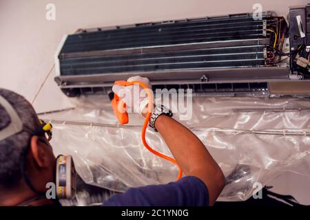 Uomo lavoratore che fa la pulizia professionale di aria condizionata. Foto Stock