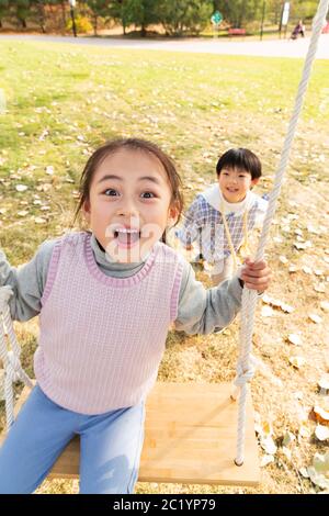 Felici i bambini sulle altalene nel parco Foto Stock