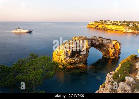 Es Pontas a Maiorca con barca ancorata nelle vicinanze del Mediterraneo. Alba con yacht e arco di roccia vicino Santanyi Maiorca. Foto Stock