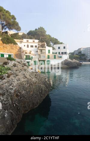 Punta rocciosa con ville private sopra il mare azzurro calmo sull'isola delle Baleari. Isola di Maiorca di acque cristalline e incredibili per nuotare. Foto Stock