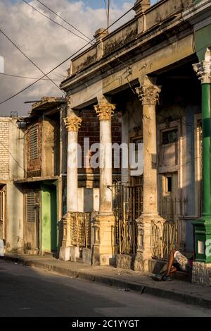 Architettura sgranata e uomo soleggiato seduto sulle scale del centro storico della città, Santiago de Cuba, Cuba Foto Stock