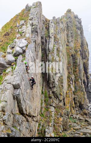 CULLEN CITTÀ MORAY COSTA SCOZIA DUE SCALATORI SU UNA PARETE ROCCIOSA UTILIZZATA PER LA PRATICA DA SCALATORI DI ROCCIA Foto Stock