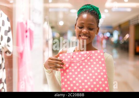 bella ragazza nera con mani che tengono borsa shopping felice nel centro commerciale Foto Stock