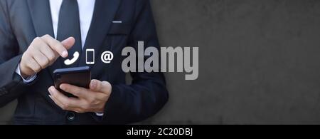 Uomo d'affari, con la mano, lo smartphone con icona (telefono cellulare e indirizzo e-mail). Concetto di servizio clienti contatto call center. Contatto informazioni Foto Stock
