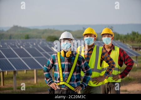 La nuova normalità del team di ingegneria elettrica sta lavorando in un impianto di pannelli solari o di riparazione fotovoltaica Foto Stock