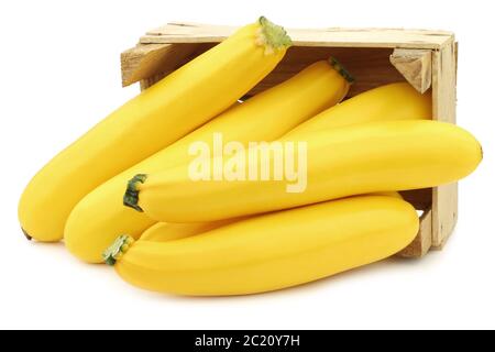 zucchine gialle in una cassa di legno su sfondo bianco Foto Stock