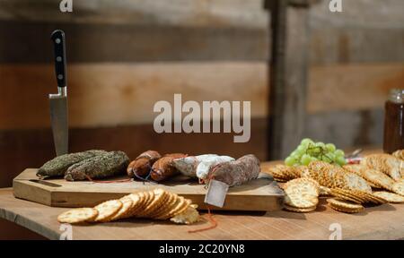 Piatto di formaggi rustico con una selezione di formaggi etichettati e salumi con uva. Foto Stock
