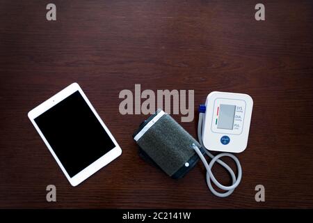 Monitor digitale della pressione sanguigna con tablet su tavolo di legno Foto Stock
