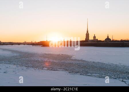Fiume Neva congelato a San Pietroburgo in inverno al tramonto con raggi di sole, Pietro e fortezza Paolo sullo sfondo. Fairway sul ghiaccio del fiume Neva. Inverno Foto Stock
