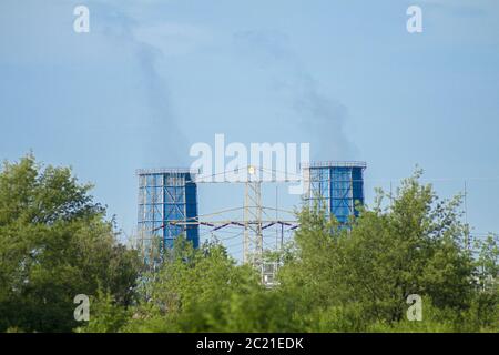 Vecchie ma ancora attive torri di raffreddamento da cui il vapore è visto da lontano con un cielo blu sullo sfondo Foto Stock