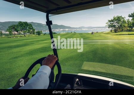 Unriconoscable Man Rides Golf Cart sul campo da golf Green Foto Stock