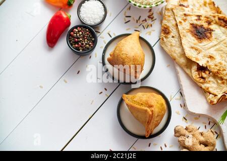 Spuntino tradizionale indiano Samosa servito in un piatto su un tavolo di legno bianco Foto Stock