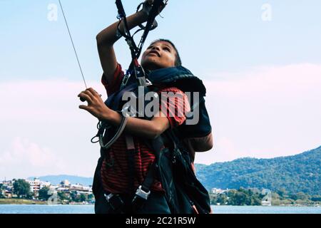 Pokhara Nepal 6 ottobre 2018 Ritratto di un giovane ragazzo nepalese che impara ad essere un pilota di parapendio nella zona di atterraggio di fronte al lago Phewa di Pokhara Foto Stock