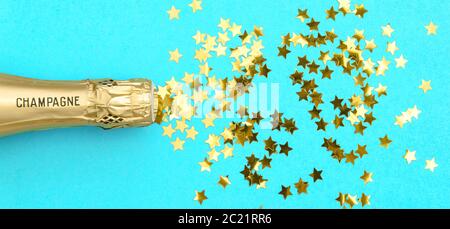 Champagme con confetti dorati su sfondo blu. Decorazione di festa Foto Stock